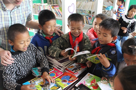 云南省宁洱县温泉小学的同学们在图书室翻阅新到的图书